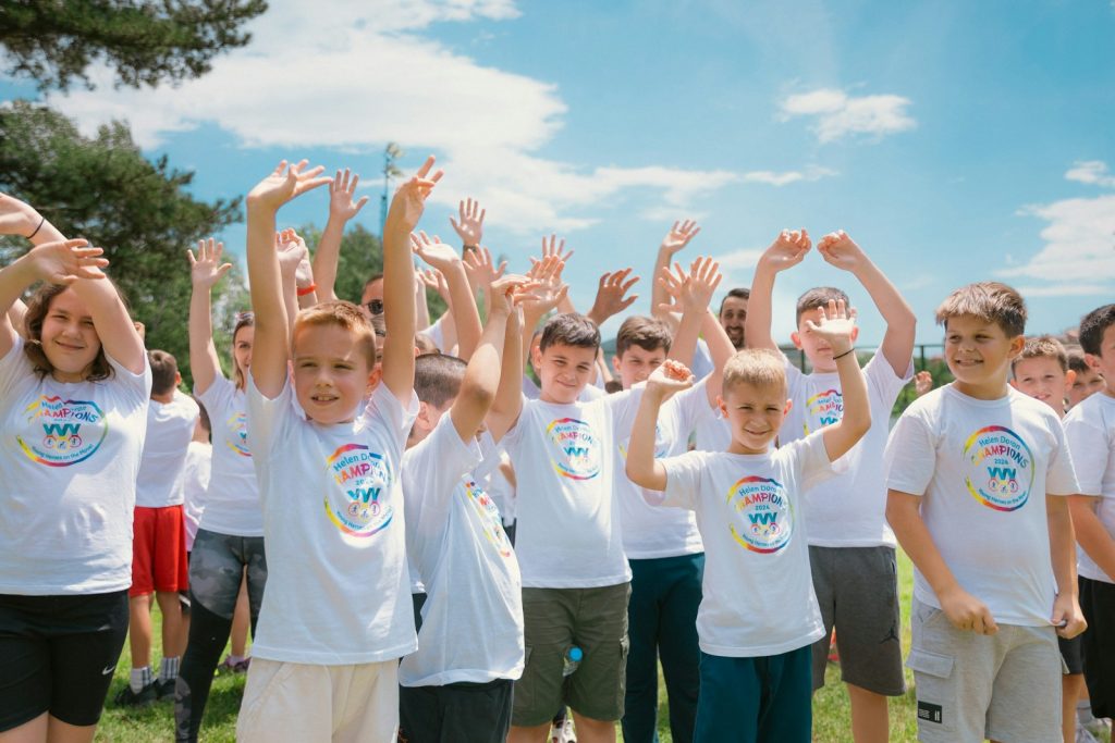 un groupe d’enfants debout dans un champ, les mains en l’air