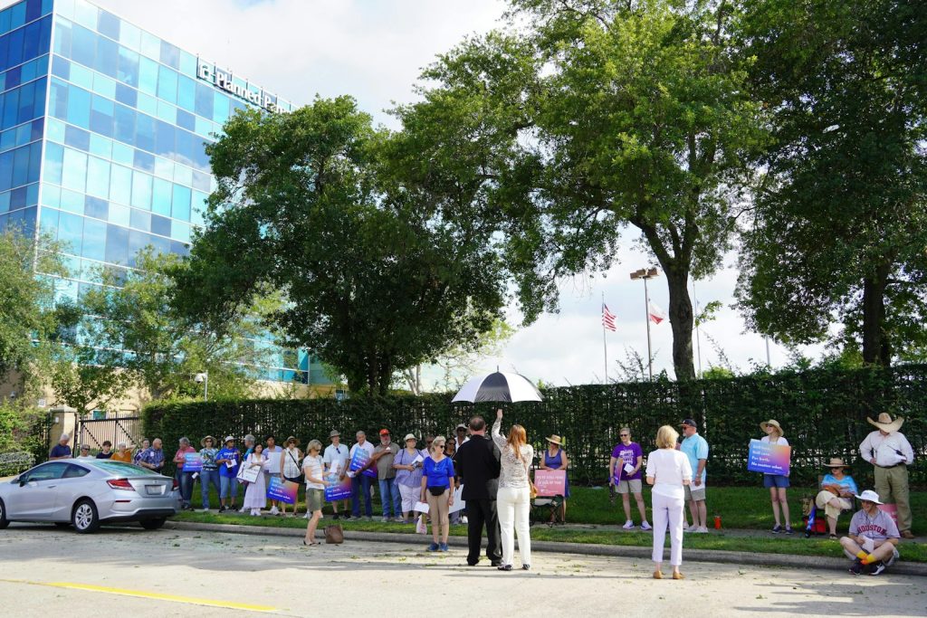 People gather outside a modern building with trees.